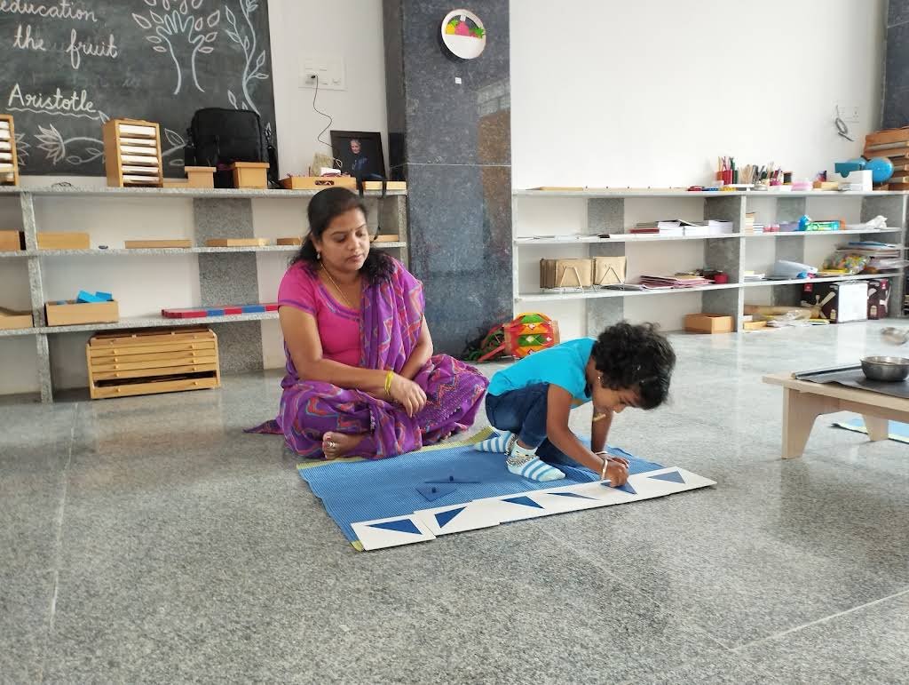 A Chandrica Montessori guide observing a child working independently